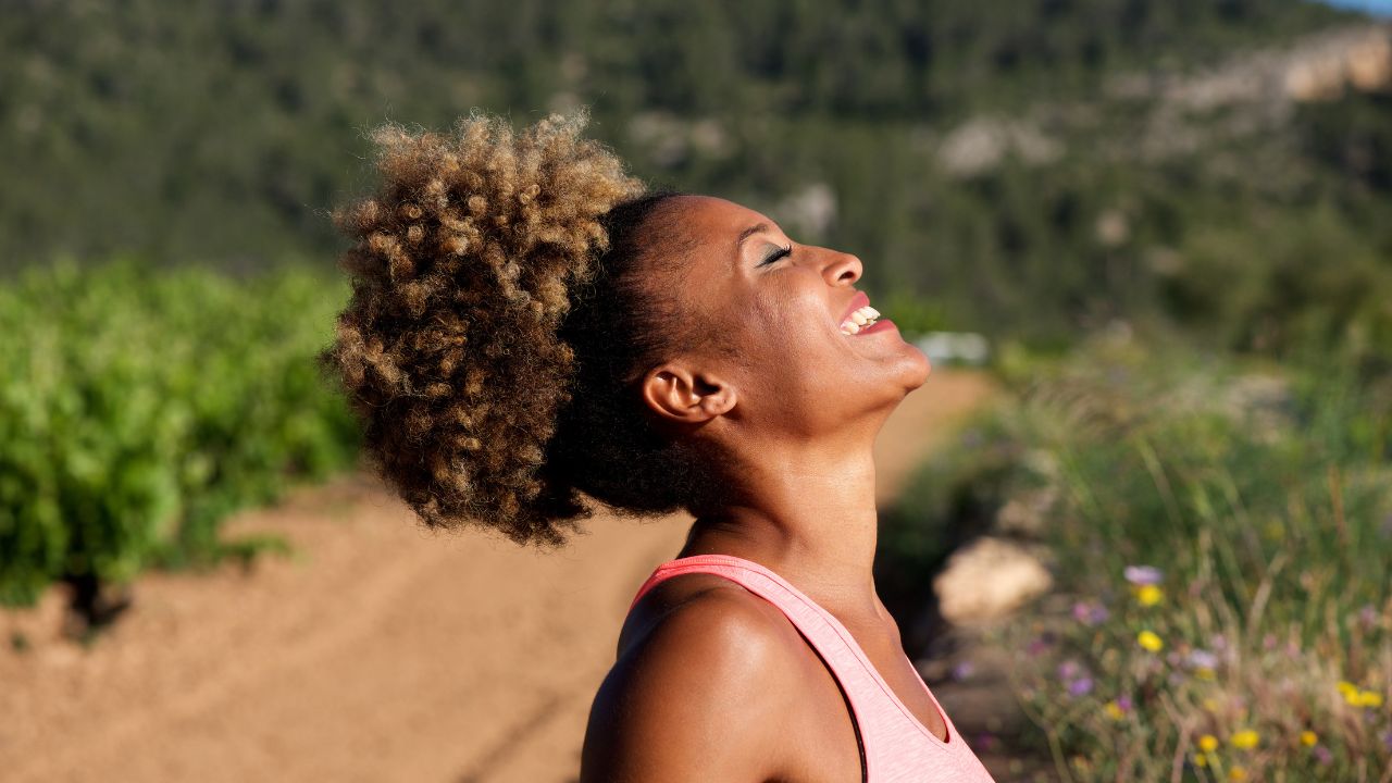 A beautiful black woman smiling with head tilted up toward the sky and she smiling